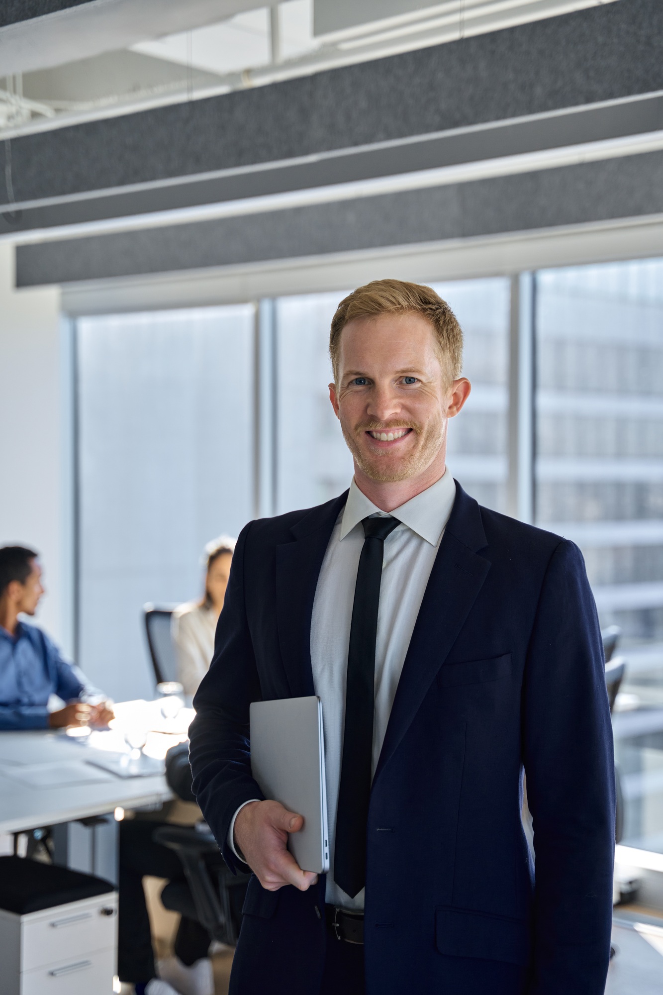 Smiling young business man manager leader standing in office. Vertical portrait